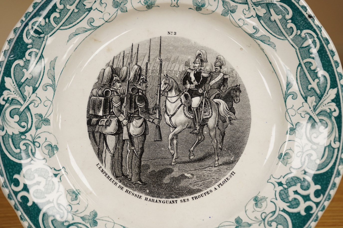 A 19th Century French military commemorative plate, transfer printed with a scene of Russian infantry soldiers, ‘L’Empereur de Russe Haranguant ses Troupes a Ploiesti’ (The Emperor of Russia inspecting his troops in Ploi